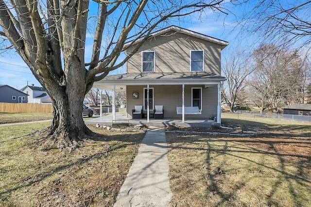 view of front of property with covered porch, a front lawn, and fence