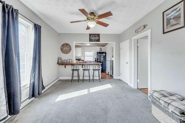 interior space with a ceiling fan, carpet, baseboards, and a textured ceiling