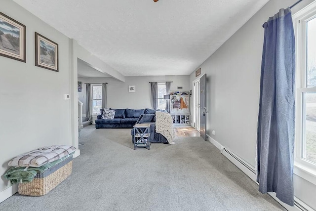 carpeted living area with a baseboard heating unit, baseboards, and a textured ceiling