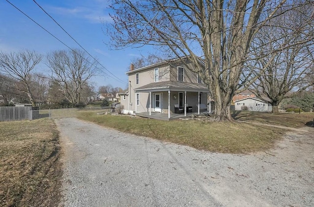 view of front facade with a front lawn, fence, a porch, a chimney, and driveway