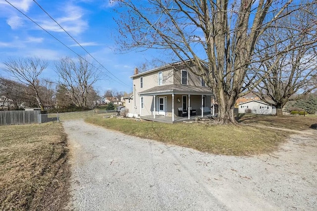 view of front of property featuring a front lawn, fence, dirt driveway, covered porch, and a chimney