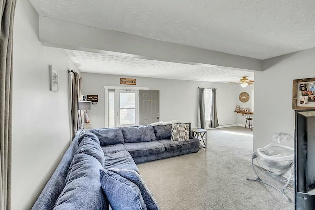 living room featuring baseboards, carpet floors, a textured ceiling, and ceiling fan