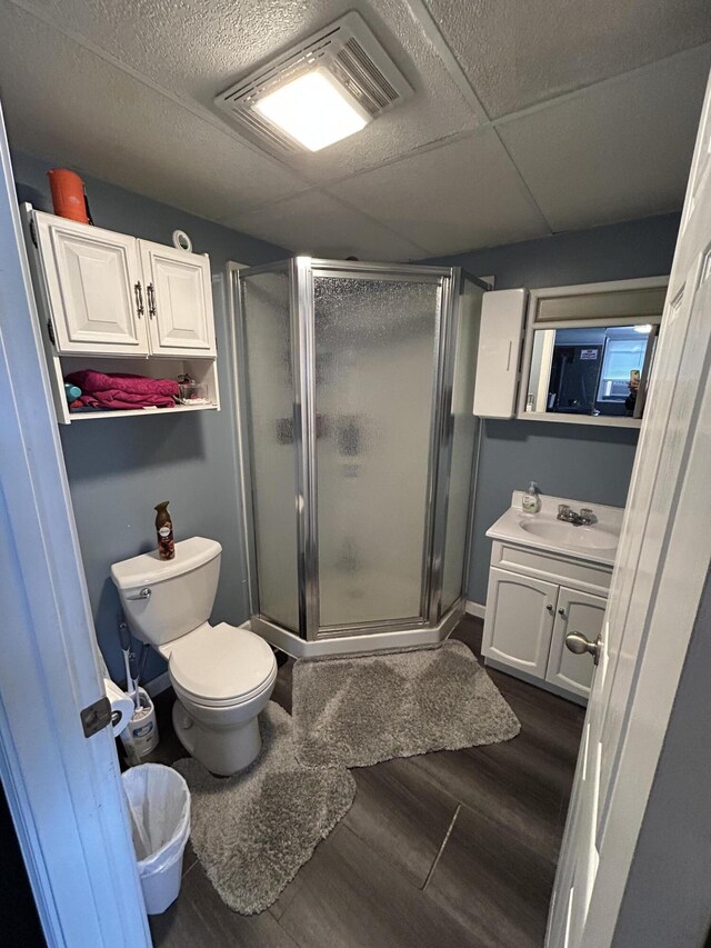 full bathroom with visible vents, a shower stall, toilet, wood finished floors, and vanity
