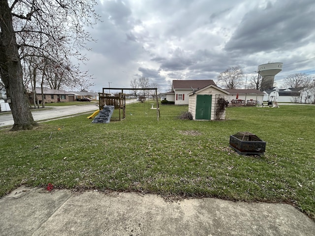 view of yard with an outbuilding, a playground, a fire pit, and a shed