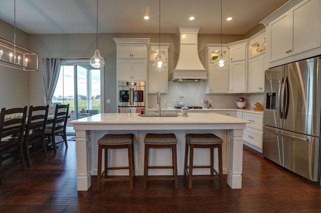 2737 Executive Dr, Troy, OH 45373 - kitchen with stainless steel appliances, a sink, custom range hood, white cabinetry, and backsplash
