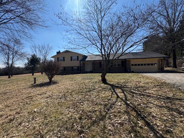 view of front of house with dirt driveway, a chimney, and a garage