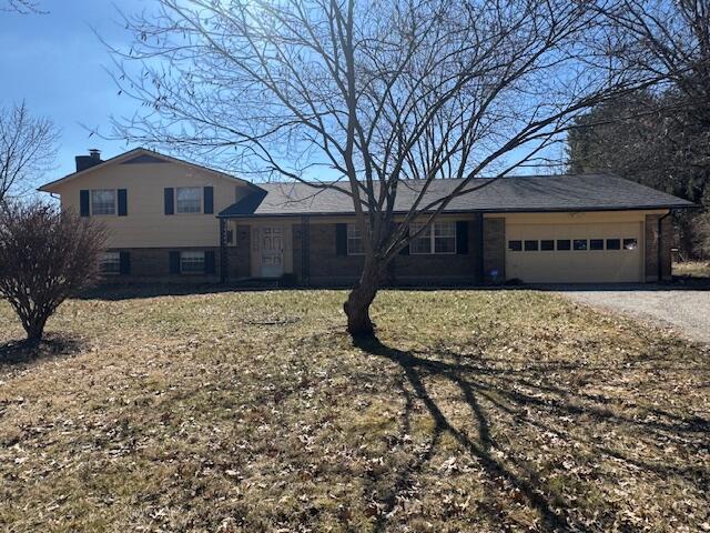 tri-level home with driveway, a chimney, and an attached garage