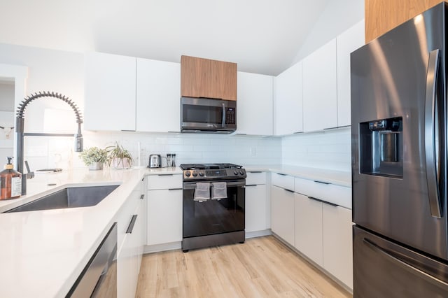 7925 Hickory Ave, Russells Point, OH 43348 - kitchen featuring stainless steel appliances, a sink, light countertops, decorative backsplash, and vaulted ceiling