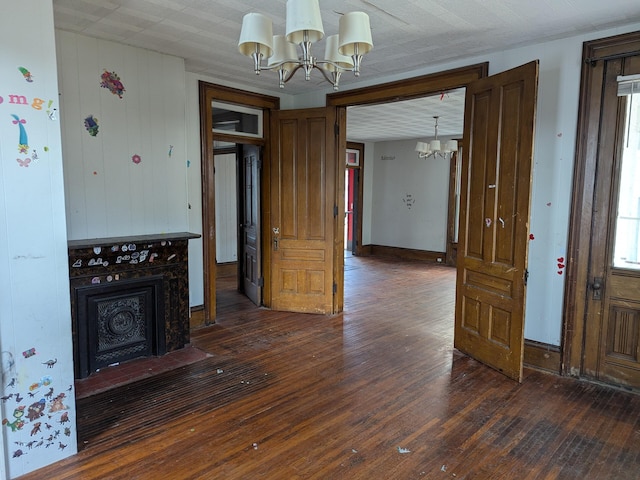 unfurnished living room with dark hardwood / wood-style flooring, a fireplace, and an inviting chandelier