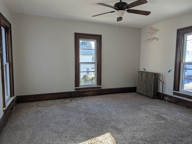 carpeted empty room featuring ceiling fan, radiator heating unit, and a healthy amount of sunlight