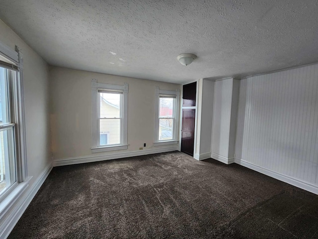 127 N Sycamore St, Union City, OH 45390 - spare room featuring dark carpet, baseboards, and a textured ceiling