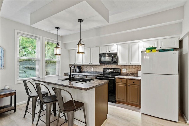 kitchen with a sink, dark countertops, light wood-style floors, and black appliances