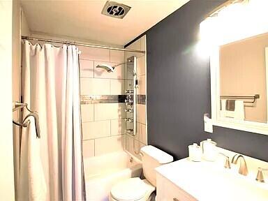 full bath featuring visible vents, vanity, toilet, and shower / tub combo with curtain