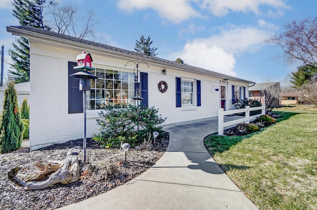 single story home featuring a front lawn, fence, and brick siding