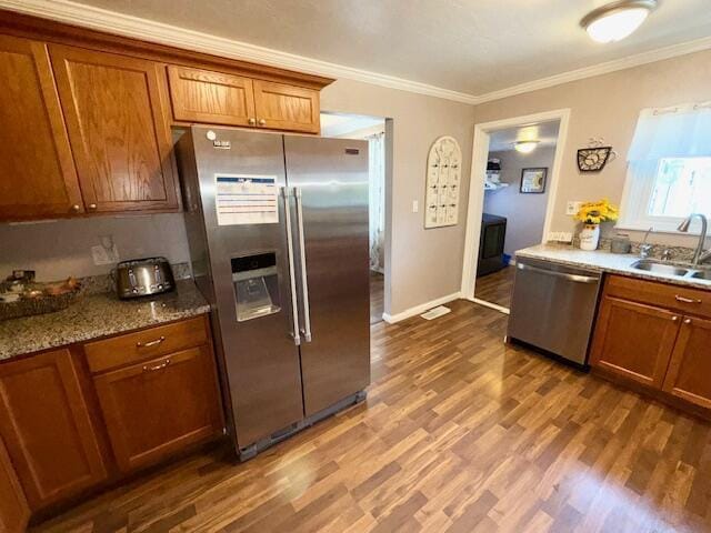 271 N Ludlow St, Covington, OH 45318 - kitchen with stainless steel appliances, brown cabinetry, ornamental molding, dark wood-type flooring, and light stone countertops