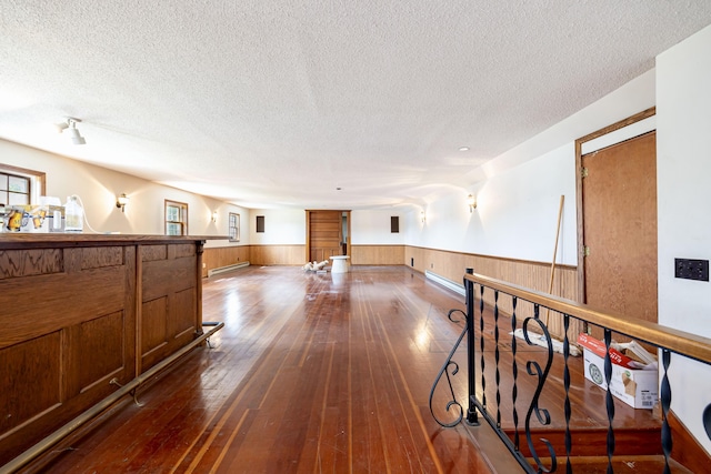103 N Boggs St, De Graff, OH 43318 - corridor featuring a wainscoted wall, a textured ceiling, dark wood-style flooring, a baseboard heating unit, and wooden walls
