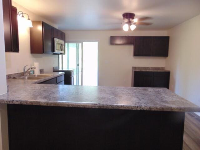 1723 Bermuda Dr, Lima, OH 45801 - kitchen featuring stainless steel microwave, a sink, a ceiling fan, a peninsula, and light stone countertops