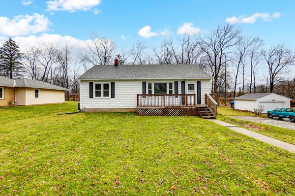 view of front of property with a wooden deck, a garage, a front yard, and an outbuilding