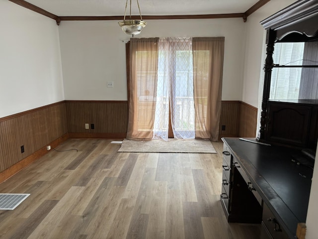 320 N Clairmont Ave, Springfield, OH 45503 - unfurnished dining area with a wainscoted wall, crown molding, light wood-style floors, and wood walls