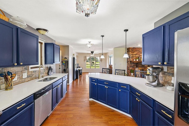 930 N Bickett Rd, Xenia, OH 45385 - kitchen featuring appliances with stainless steel finishes, decorative backsplash, blue cabinets, light wood-style floors, and a peninsula