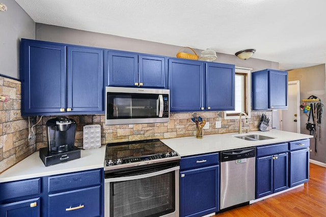 930 N Bickett Rd, Xenia, OH 45385 - kitchen with stainless steel appliances, blue cabinetry, tasteful backsplash, light wood-type flooring, and light countertops