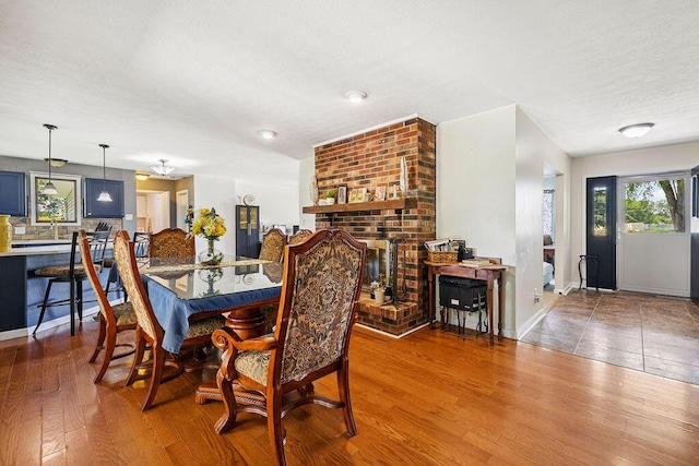 930 N Bickett Rd, Xenia, OH 45385 - dining area featuring wood finished floors, a brick fireplace, and a textured ceiling