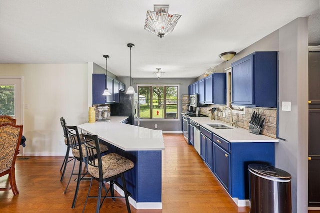 930 N Bickett Rd, Xenia, OH 45385 - kitchen with blue cabinets, stainless steel appliances, a kitchen breakfast bar, light countertops, and light wood-style flooring