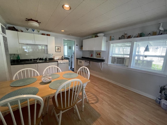 dining area with crown molding, sink, light hardwood / wood-style floors, and cooling unit