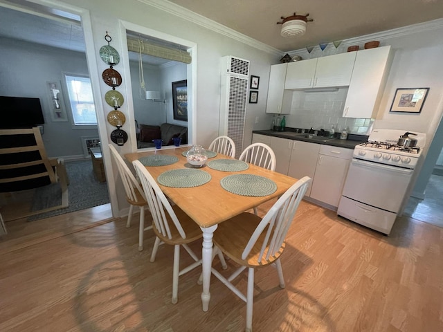 dining space with ornamental molding, sink, and light hardwood / wood-style floors