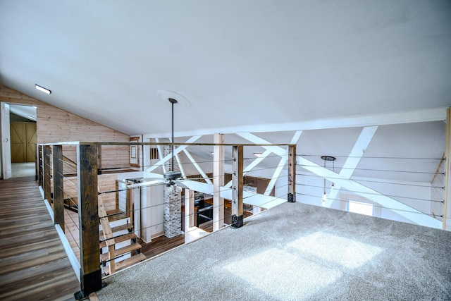 staircase featuring vaulted ceiling and wooden walls