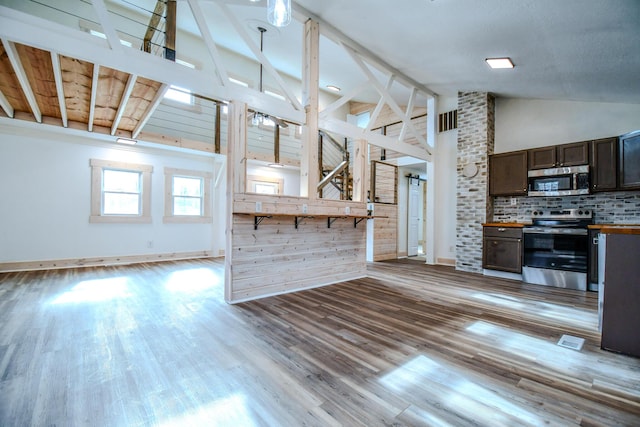 kitchen with tasteful backsplash, light wood-type flooring, high vaulted ceiling, and appliances with stainless steel finishes