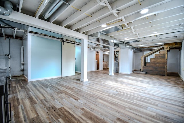 basement with a barn door and hardwood / wood-style floors