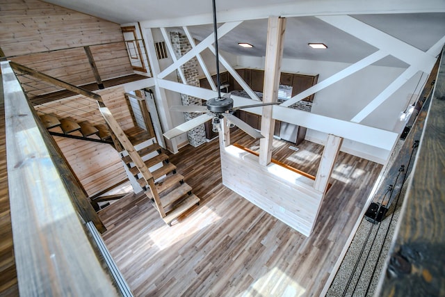 staircase featuring lofted ceiling, wood-type flooring, and wood walls