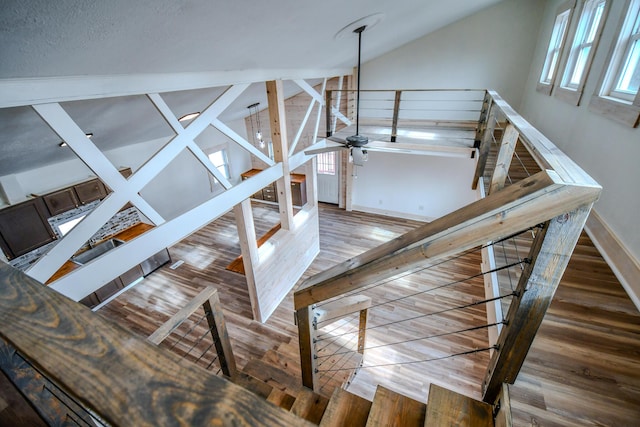 stairs featuring hardwood / wood-style flooring, ceiling fan, sink, and vaulted ceiling