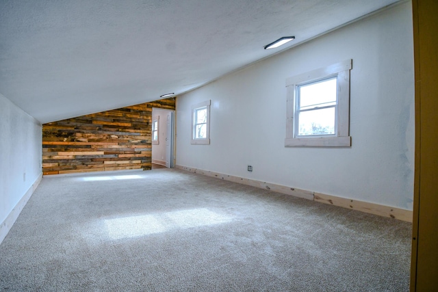 spare room with vaulted ceiling, carpet floors, a textured ceiling, and wood walls