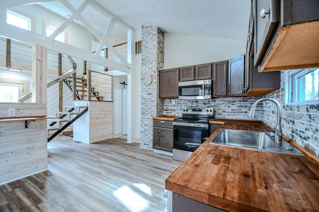 kitchen with stainless steel appliances, sink, dark brown cabinetry, and light hardwood / wood-style flooring