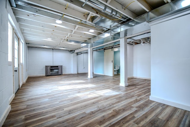 basement featuring wood-type flooring and heating unit