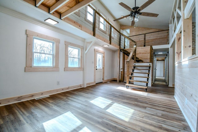 unfurnished living room featuring hardwood / wood-style floors, ceiling fan, and a high ceiling