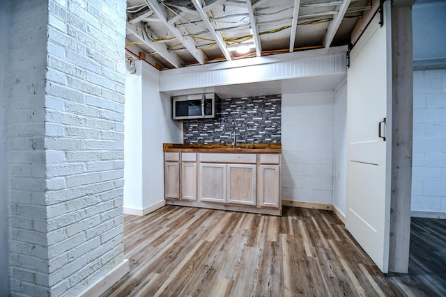 kitchen featuring hardwood / wood-style floors, sink, and brick wall