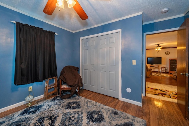 bedroom with hardwood / wood-style floors, ornamental molding, a closet, and a textured ceiling