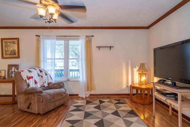 sitting room with ceiling fan, ornamental molding, and wood-type flooring