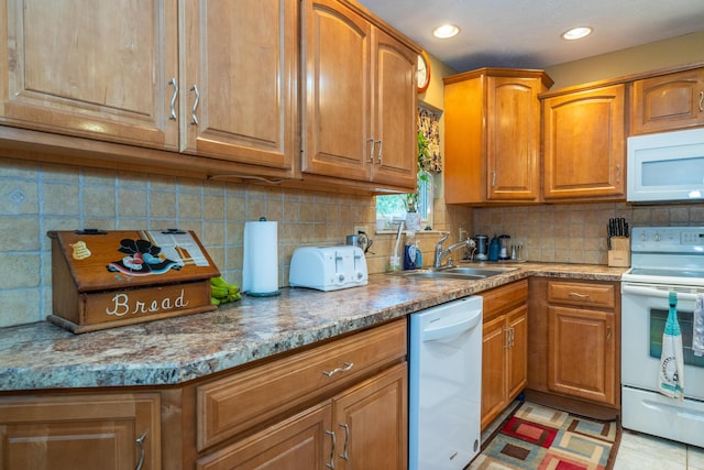 kitchen featuring light stone counters, sink, white appliances, and decorative backsplash