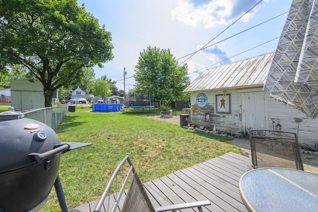 208 E Main St, Belle Center, OH 43310 - fenced backyard featuring a trampoline, an outbuilding, and a deck
