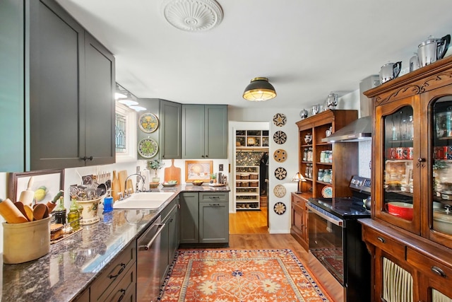 1639 E Mile Rd, Springfield, OH 45503 - kitchen with stainless steel appliances, light wood-style floors, extractor fan, dark stone countertops, and a sink