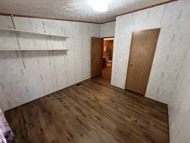 unfurnished room with a textured ceiling, wood finished floors, and ornamental molding