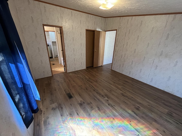 spare room featuring visible vents, a textured ceiling, wood finished floors, and crown molding