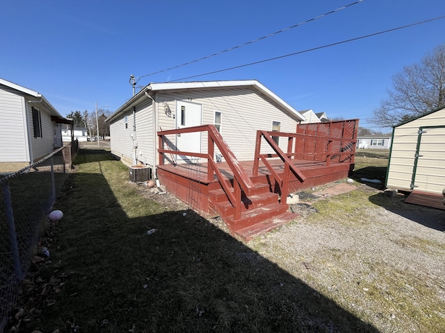 back of property with an outbuilding, a lawn, and a deck