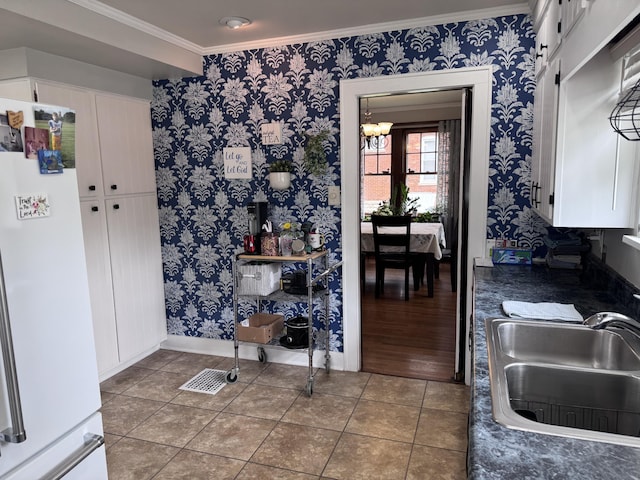 607 W S St, Saint Marys, OH 45885 - kitchen featuring freestanding refrigerator, a sink, crown molding, dark countertops, and wallpapered walls
