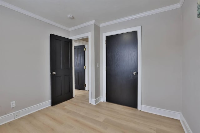 unfurnished bedroom featuring crown molding, baseboards, and light wood-type flooring