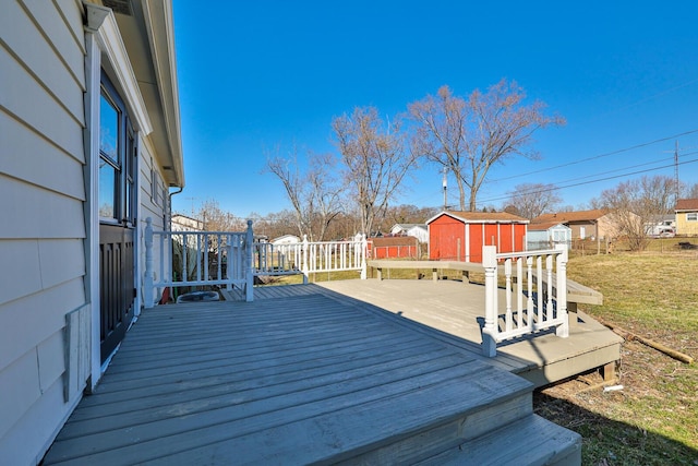 wooden deck with a storage shed, fence, an outbuilding, and a residential view